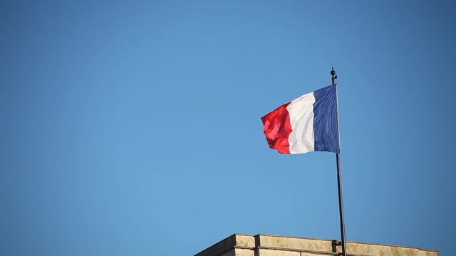 french flag waving on blue sky on top of the building
