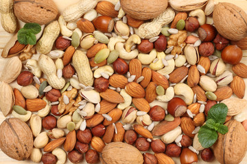 mix almonds, cashew nuts, hazelnut, peanuts, walnuts, pistachio on wooden background. Top view with copy space