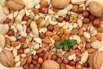 mix almonds, cashew nuts, hazelnut, peanuts, walnuts, pistachio on wooden background. Top view with copy space