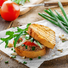 Toast sandwich with tuna, tomato, onion and arugula. Traditional healthy food made of fish, vegetables and grilled bread.