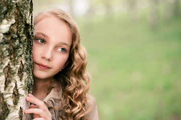 portrait of beautiful girl standing close to tree