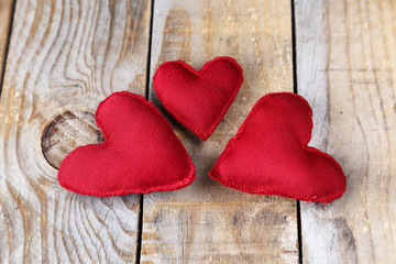 Three red hearts made by hand on an old wooden table

