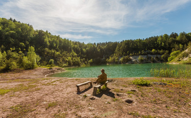 a man sits on the shore of the lake