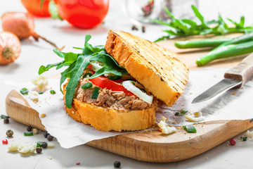 Classic tuna salad sandwich with tomato, onion and arugula on a white table. Delicious healthy meal made of fish, vegetables and toasts.