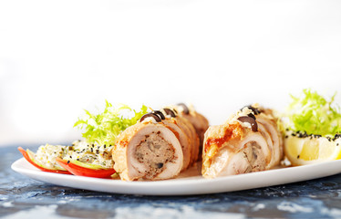 Delicious chicken rolls with lemon and tomatoes on a blue background. The concept of nourishing food.