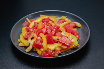 Fresh summer salad on a black plate with on a black background.