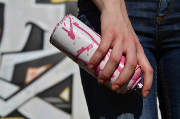 Photo of a girl's hand with aerosol paint cans in hands on a graffiti wall background. The concept of street art and use of aerosol paints. Graffiti art shop background image