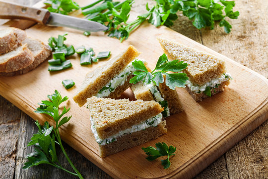 Cream cheese sandwiches with fresh parsley and green onion on a rustic table. Healthy homemade appetizer. Close-up shot.