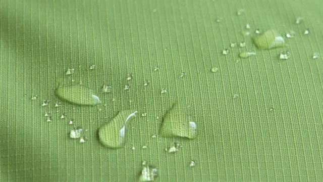 Drops of water fall on the green waterproof fabric rip-stop. Close-up