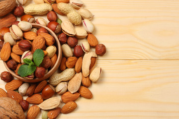 mix almonds, cashew nuts, hazelnut, peanuts, walnuts, pistachio on wooden background. Top view with copy space