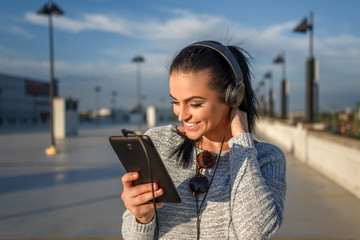 Woman listening music by headphones and tablet outdoor