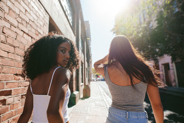 Young women walking together on sidewalk