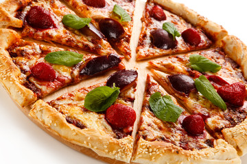 Pizza with plums and strawberries on white background