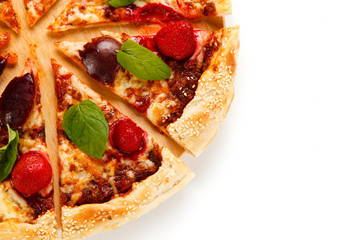 Pizza with plums and strawberries on white background