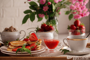 Syrniki with strawberry and green tea cup on a light background