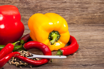Sweet and spicy peppers on wooden background in studio photo. Raw healthy food