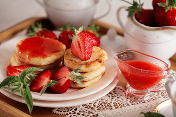 Syrniki with strawberry and green tea cup on a light background