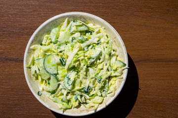 Spring salad with cabbage, cucumber, green onion, parsley and mayonnaise on wooden table