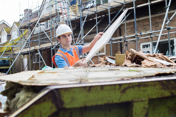 Builder On Site Putting Waste Into Rubbish Skip