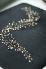 sprig, a beautiful wedding hair accessory, handmade, transparent, pink crystals, beads on a Golden wire on black background, top view