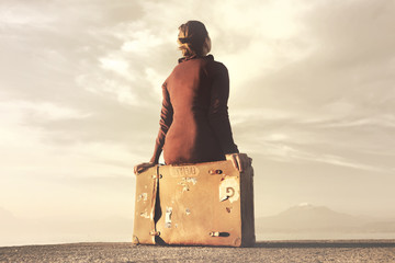 Traveler woman arriving at destination relaxes sitting on her suitcase
