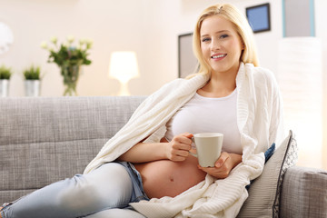 Obraz na płótnie Canvas Happy pregnant woman resting on sofa