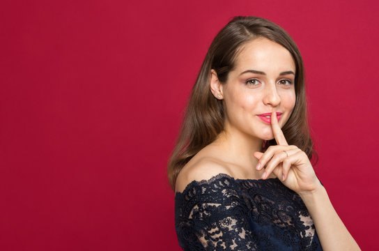 Beautiful girl looking at camera and holding finger near mouth