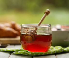 Closeup of beautiful honey in jar with honey spoon on table with kitchen towel. Breakfast. Kitchen Background.