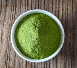 Green tea powder in cup on wood table