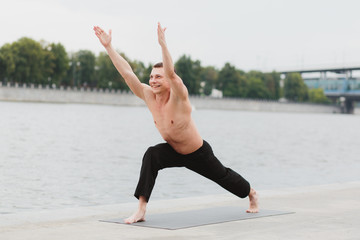 Obraz premium a young man practicing yoga asanas in the city on the waterfront
