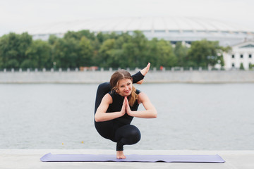 a young woman practicing yoga asanas in the city on the waterfront