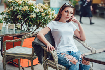 Attractive girl siting in a street cafe at a table. Mock-up.