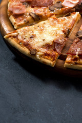 Pizza with cheese and sausage on a black background, vertical