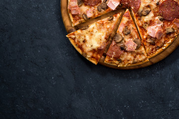 Pizza with cheese and sausage on a black background, top view