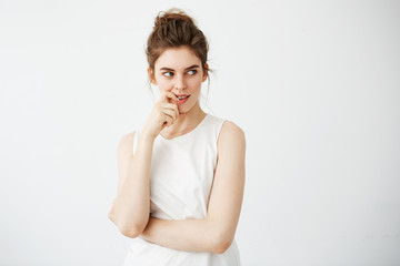 Portrait of young beautiful girl smiling thinking dreaming touching her chin over white background.