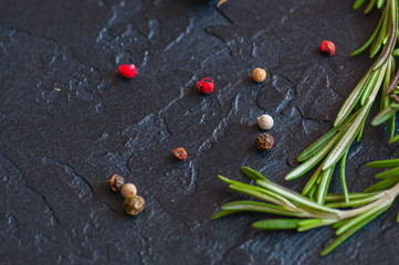 Close up of young garlic cloves, peppercorns, rosemary on a gray stone background. 