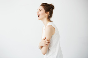 Obraz premium Happy cheerful young girl with bun smiling laughing over white background. Crossed arms.
