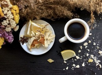 Crashed macaroons on a white plate with coffee and some dry flowers