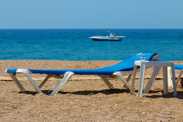 Sunbed on rocky beach, near the ocean.