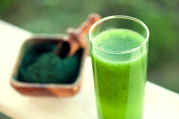 Green smoothie with spirulina on wood background