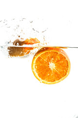 orange halves falling into water on white background