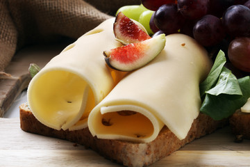 Bread with slices of cheese, some grapes and fig for lunch table. Sharing antipasti on party or summer picnic time
