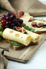 Bread with slices of cheese, some grapes and fig for lunch table. Sharing antipasti on party or summer picnic time