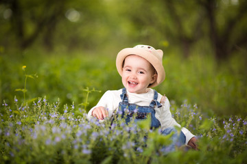 A little girl sitting in the garden and sniffs flowers, emotions, joy