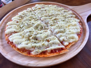 Sliced hawaiian pizza with ham and pineapple on dark wooden table