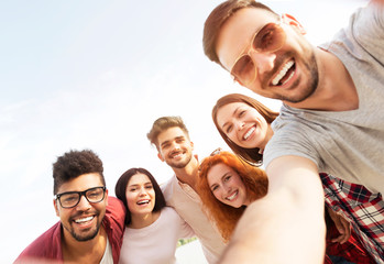 Group of young people taking a selfie outdoors on the beach, having fun
