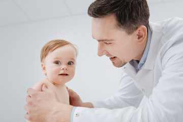 Fototapeta premium Delighted experienced pediatrician working with adorable patient