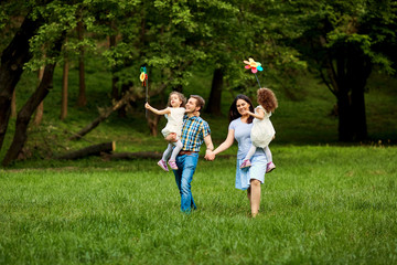 Naklejka na ściany i meble Happy family walking playing in summer park.