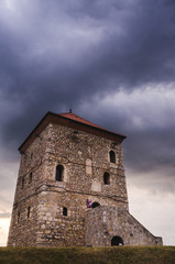 Old tower on the hill above the city under the cloudy sky