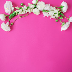 Frame wreath made of white flowers on pink background. Flat lay, top view. Flower pattern of ranunculus and snapdragon